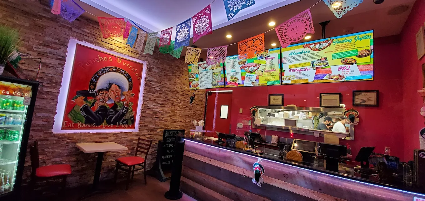 Inside Margarita's Mexican Restaurant — colorful papel picado banners, brick walls, and the kitchen counter